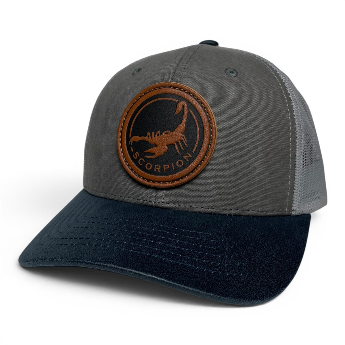 Scorpion leather patch trucker hat with charcoal front, navy brim, and gray mesh back