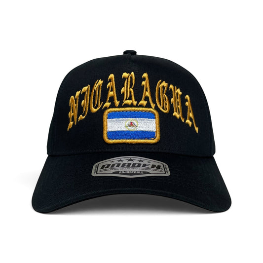 A black baseball cap featuring gold embroidered 'NICARAGUA' text and a rectangular patch of the Nicaraguan flag on the front. 